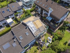 Houses in suburban location with a roof under construction seen from the air, roof renovation,