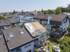 House with scaffolding and partially open roof in a suburban residential area, roof renovation,