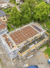View of a building under construction, surrounded by extensive vegetation and construction site