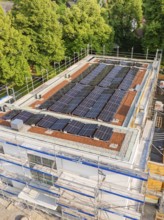 View of a construction site with solar panels on the roof, surrounded by green trees, Hirsau, Calw,