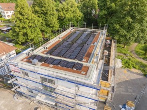 Construction site with solar panels on the roof, surrounded by trees and village houses, Hirsau,