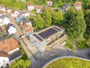 Aerial view of a construction site with solar panels, surrounded by village architecture and