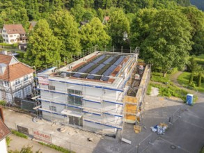 Multi-storey building with solar panels in a green environment, construction site in the