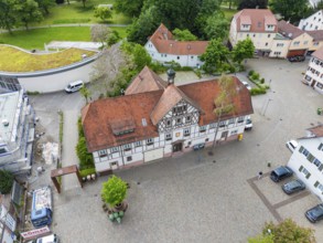 Historic half-timbered building with red roof, surrounded by cobbled streets and greenery, Hirsau,