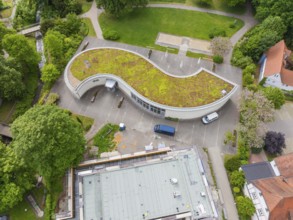 Architecturally curved building with green roof and vehicles in the car park, Hirsau, Calw, Germany