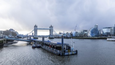 Tower bridge rising above river thames with city hall and modern buildings in background, capturing