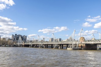 Modern pedestrian golden jubilee bridges flanking the railway hungerford bridge over the river