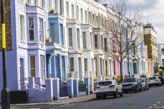 Pastel colored houses create a picturesque scene along a london street, showcasing the city's