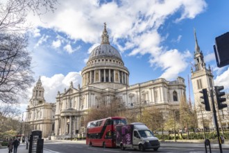 Red double decker bus driving on a street next to st paul's cathedral in london, uk, on a sunny