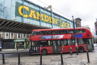Iconic red double decker bus driving through camden town in london, under the bridge with the