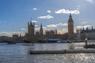 Westminster palace with big ben and westminster bridge over river thames under a blue sky in