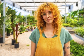 Confident young female gardener working in a vibrant greenhouse, surrounded by thriving plants and
