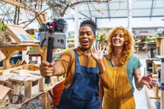 Two happy saleswomen waving at the camera while filming a video for social media marketing in a pet