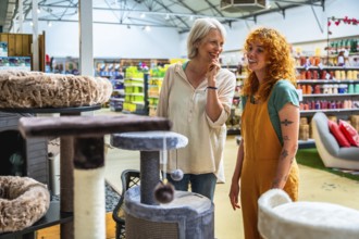 Happy senior woman selecting a cat tree while receiving assistance from a friendly shop assistant