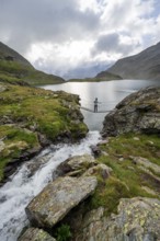 Mountaineer standing on a suspension bridge, mountain stream and mountain lake Wangenitzsee,