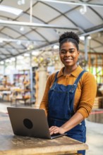 Confident young woman managing greenhouse inventory using a laptop, showcasing modern agriculture