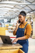 Confident black female employee managing orders and assisting customers in a garden center, using
