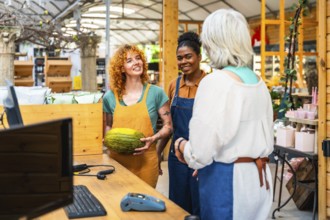 Two young shop assistants engaging with a customer while showcasing a fresh melon in a vibrant