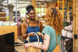 Friendly shop assistant holding credit card reader while customer making contactless payment in a