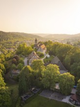 Aerial view of a village with a church surrounded by greenery at sunset, event and wedding location