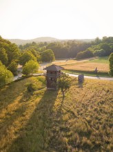 A wooden tower in a grassy landscape with long shadows and soft evening light, event and wedding