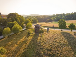 A wooden tower stands in a spacious meadow under the warm evening sun, event and wedding location