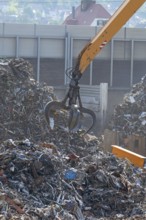 Hydraulic crane lifts scrap metal at the scrap yard in the background City of Plochingen