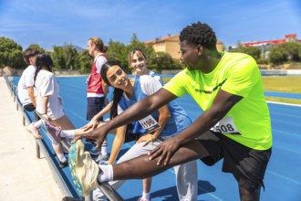 Runners stretching their legs on a sunny running track, preparing for an upcoming race and