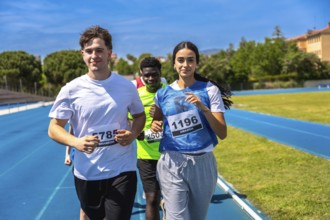 Group of athletes running on a blue track during a sports competition, demonstrating teamwork and