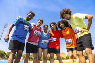 Diverse group of athletes embracing teamwork and camaraderie on a running track, celebrating