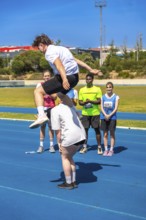 Young athlete jumps over a teammate on a track, showcasing teamwork and athleticism during a track