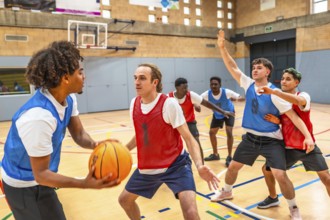Group of young basketball players engaging in an intense match within a gymnasium, showcasing