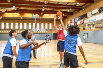 Basketball players practicing shooting and defending during training session on a basketball court