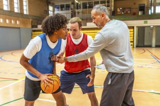 Basketball coach holding clipboard explaining game strategy to two players practicing during