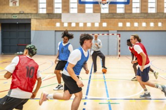Group of young basketball players running on court during training session with coach watching and
