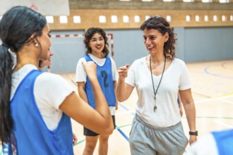 Female basketball coach motivating her team during training, encouraging players and giving support