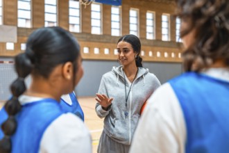 Basketball coach explaining game strategy to her team players during training in a basketball court