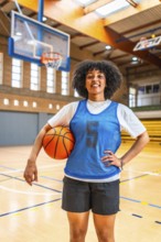 Young woman basketball player smiling while holding a ball on the court, exuding confidence and
