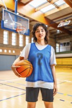 Young asian woman basketball player holding a ball in an indoor court, ready for training or