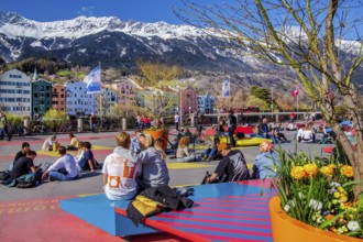 Sun-seekers on the market square on the banks of the Inn in front of the Nordkette mountain range