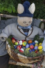 Bunny with egg basket on a bench, Easter decoration in a village in Upper Franconia, Bavaria,
