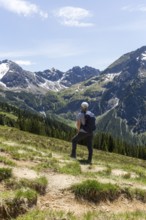 Hikers on a meadow in front of an impressive alpine backdrop in Kleinwalsertal, Austria