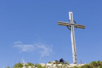 Summit cross of the Kuhgehrenspitze in Mittelberg rises in front of a bright blue sky in