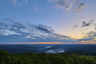 Wide landscape with wooded hills at dawn, peaceful sky with cloud formations, Katzenbuckel,