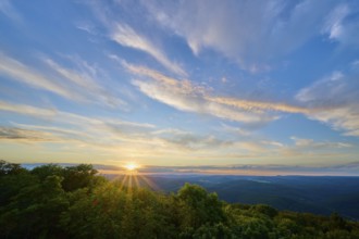 Sunset over mountains with dramatic clouds and lush greenery in the foreground, Katzenbuckel,