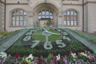Flower clock made of blooming flower-bed with flower bed, garden art, clock face, information board