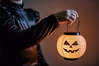 Girl in witch black costume holding glowing pumpkin lantern. generative ai, AI generated