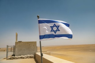 Israeli flag waving in desert wind with military checkpoint in background. Generative ai, AI