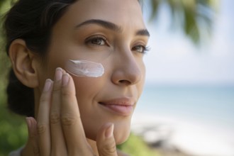 Close up of young woman applying sunscreen on her nose. Beach portrait capturing sun care and