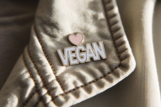 Close-up of pin with text vegan and herat on soft cotton jacket. A symbol of compassionate